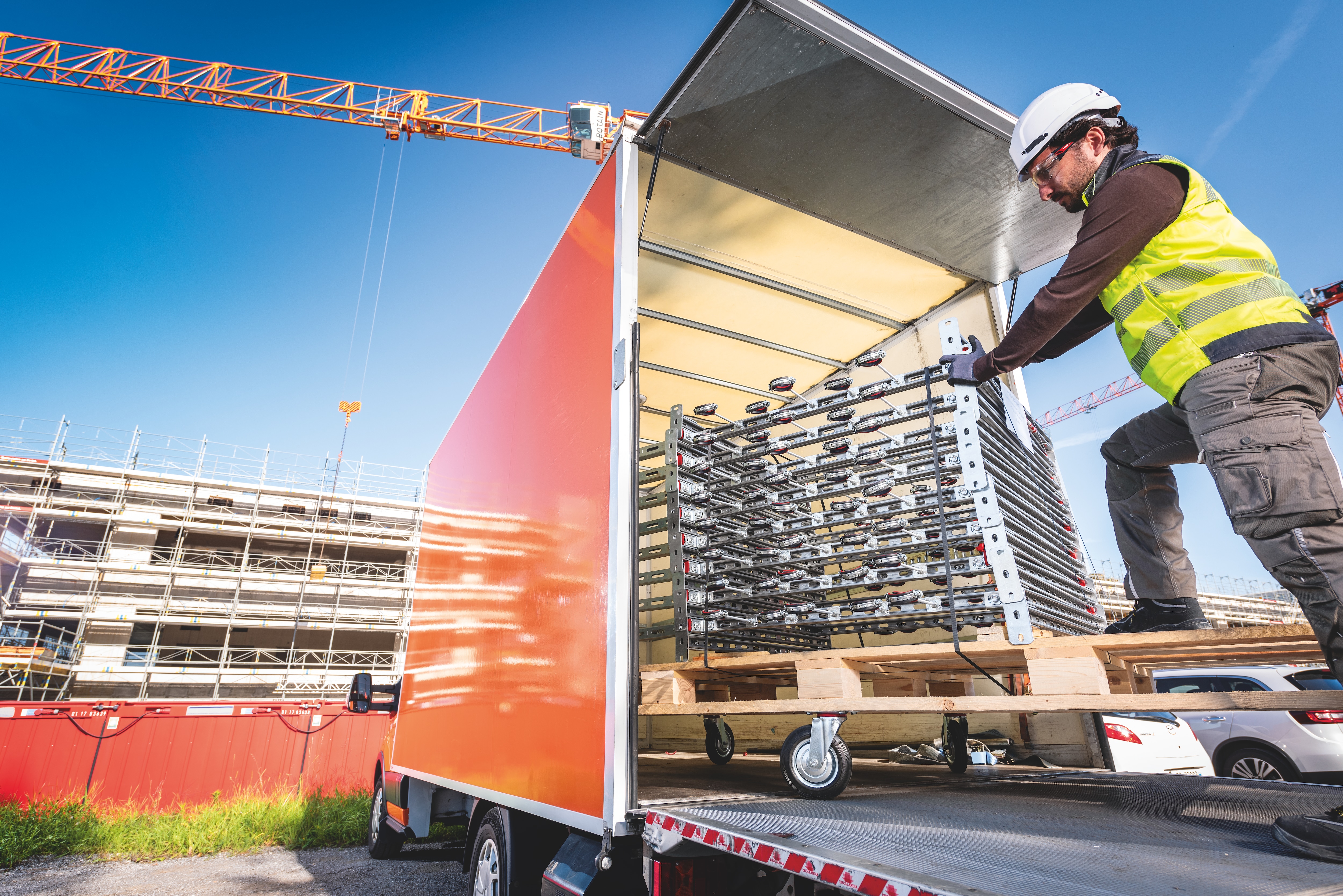 Pracovník vykladajúci predmontované modulárne systémy podpier z nákladného auta