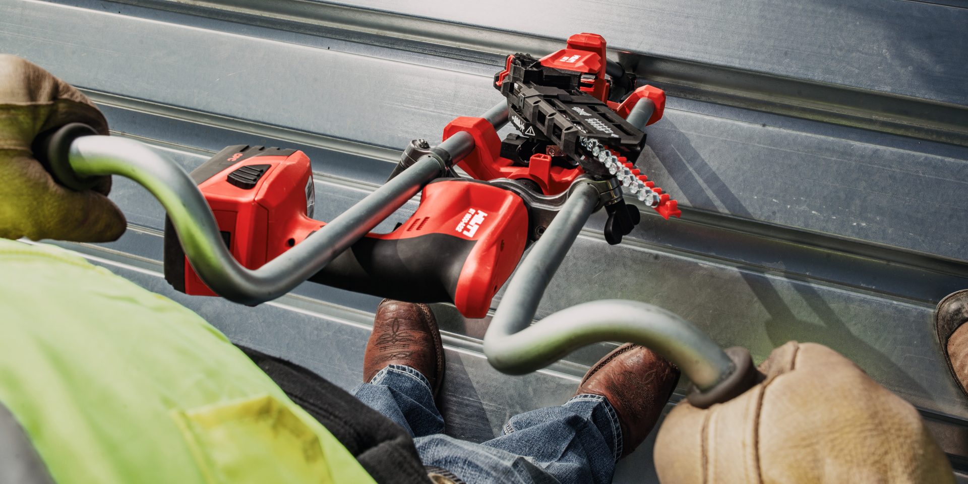 Pracovník na plechové střeše používá šroubový upevňovací systém Hilti (rukojeť SDT pro práci ve stoje) k upevnění opláštění